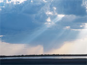 A shaft of sunlight pierces gathering clouds in the Okavango Delta, Botswana.
